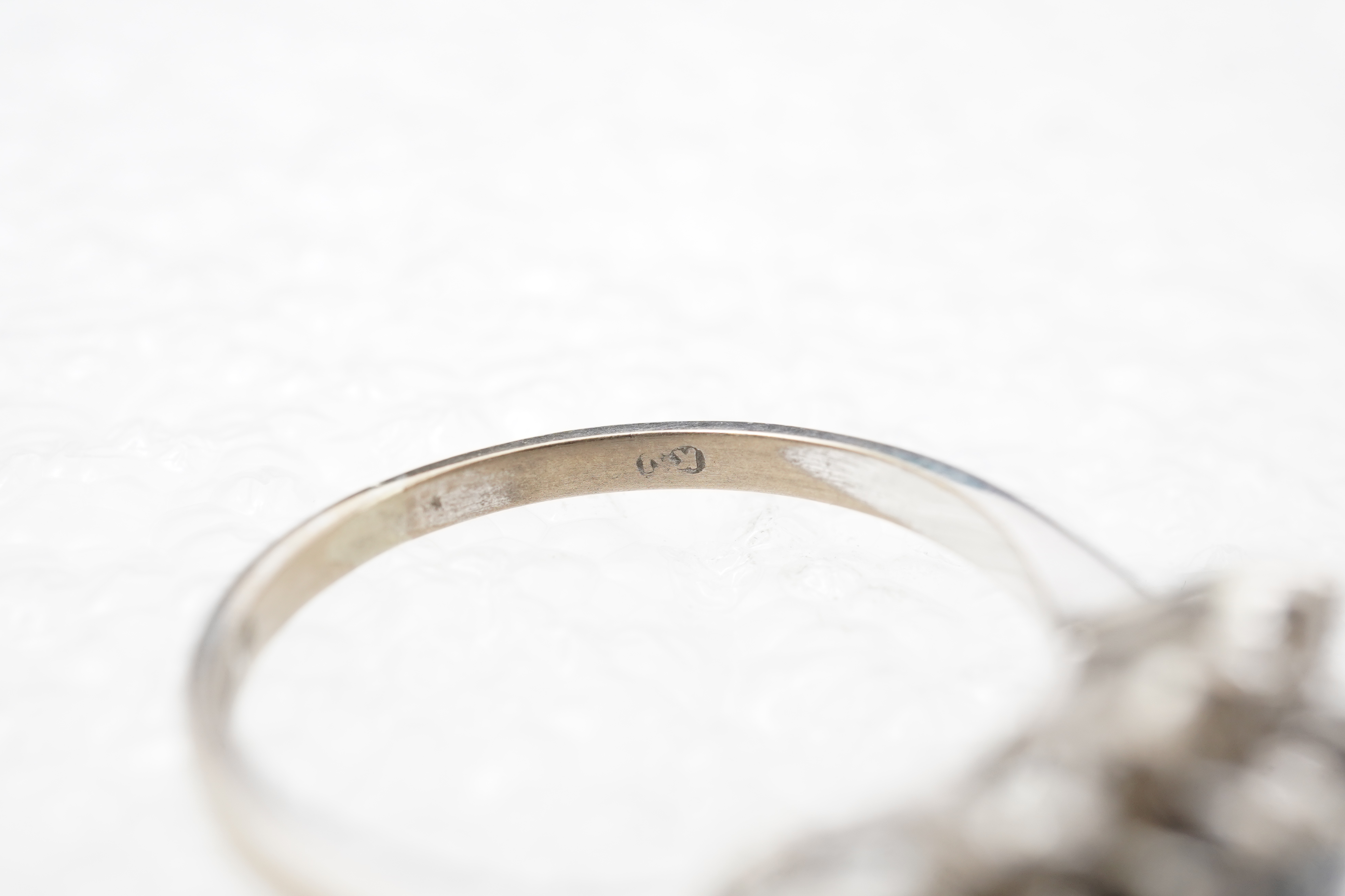 A sapphire and diamond ring, set with three circular-cut and oval sapphires, within a border of brilliant-cut diamonds totalling approximately 0.40 carats, mounted in 18ct white gold, size M1/2, British hallmarks, gross